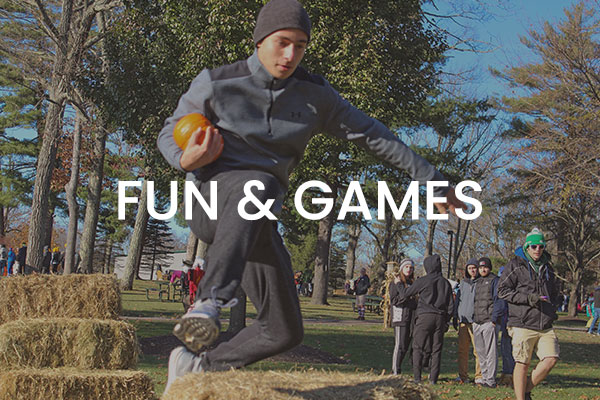 Man jumping over a hay bale. Text: fun and games.