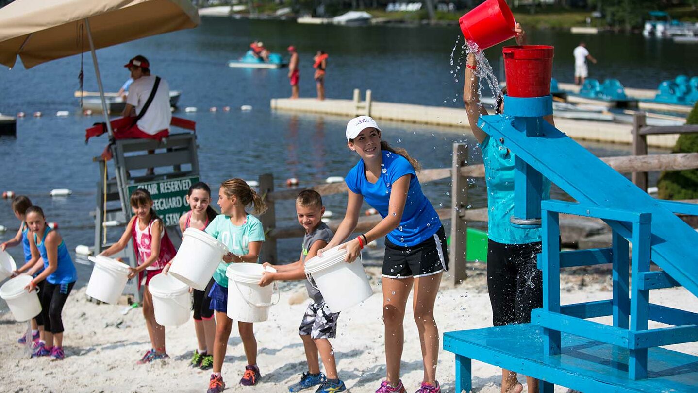 Kids forming a bucket line on the beach for a group game.