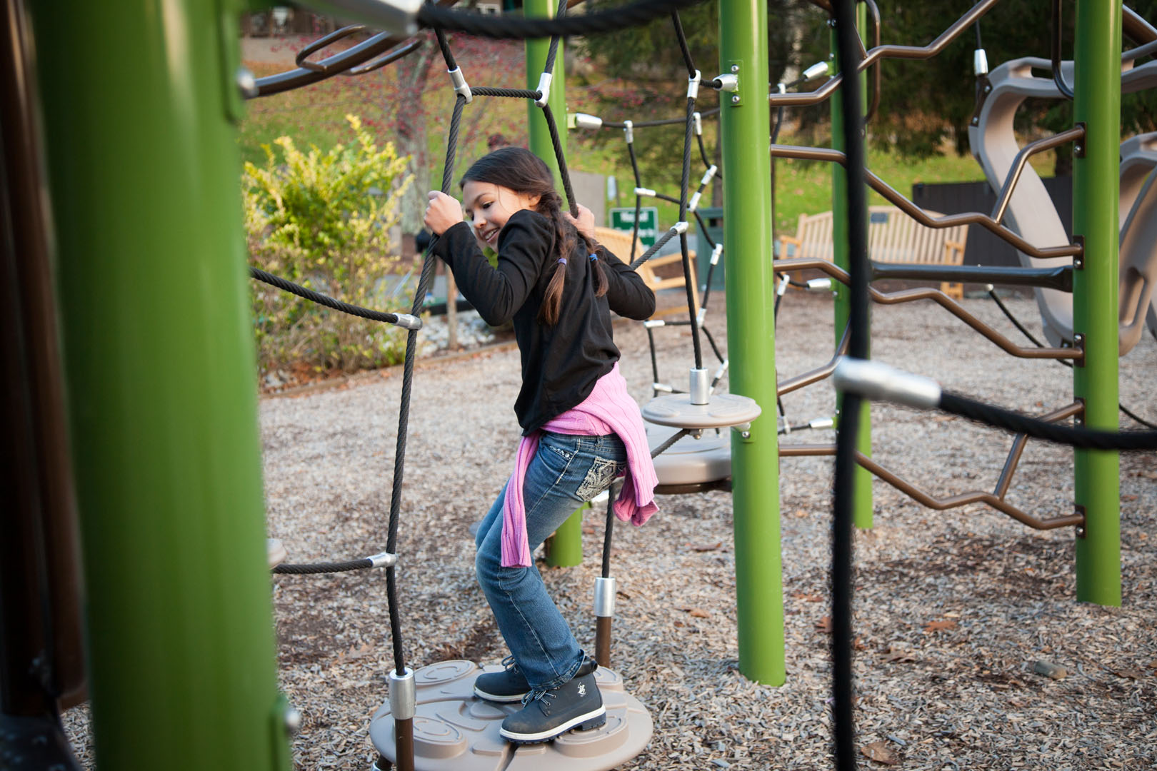 Young woman pushing toddler in a swing.