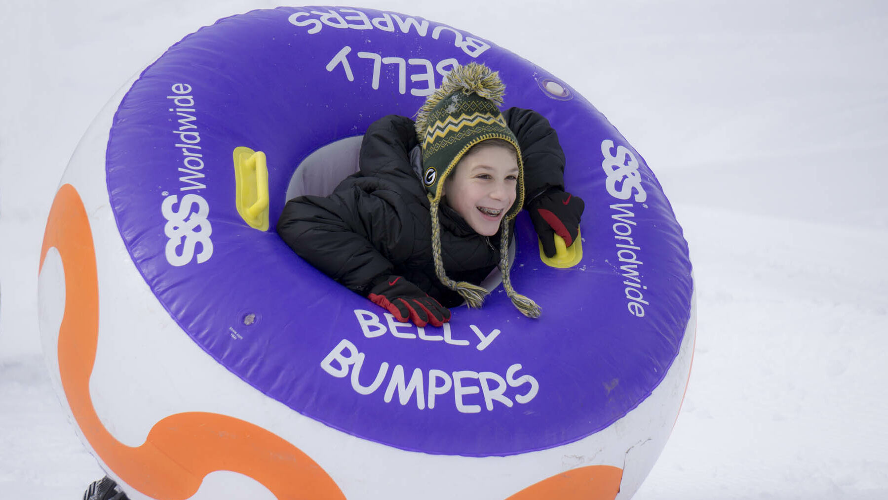 Young person in a belly bumper inner tube in winter.