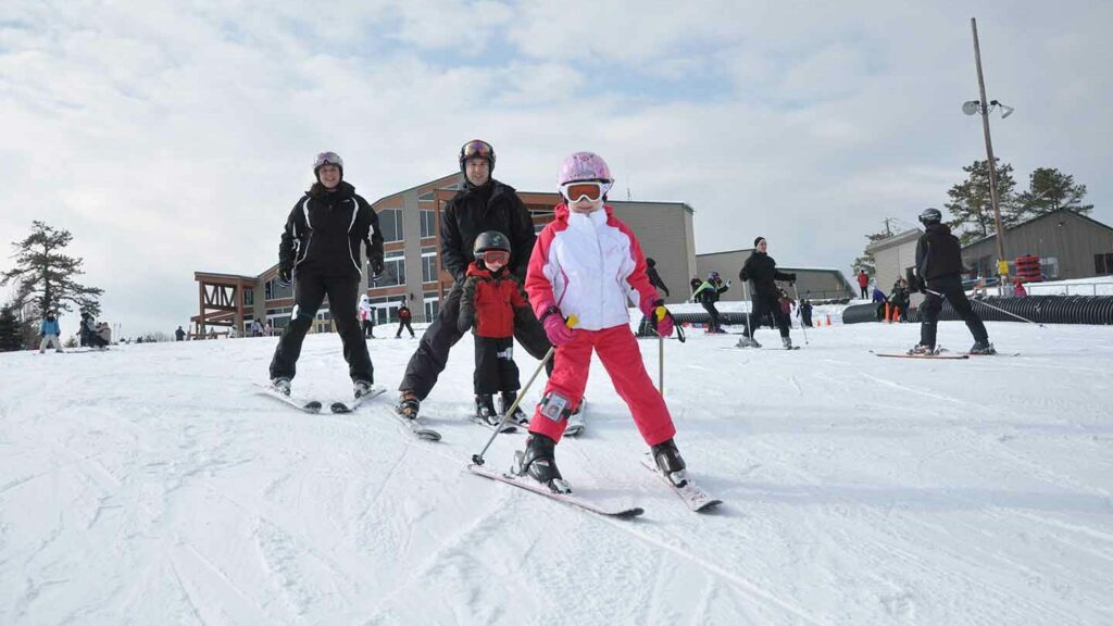 Children and adults skiing on beginner hill.