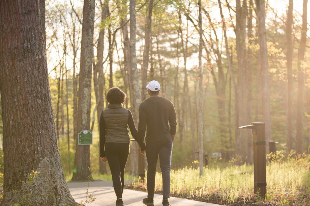Couple holding hands on nature trail during a Poconos honeymoon at Woodloch