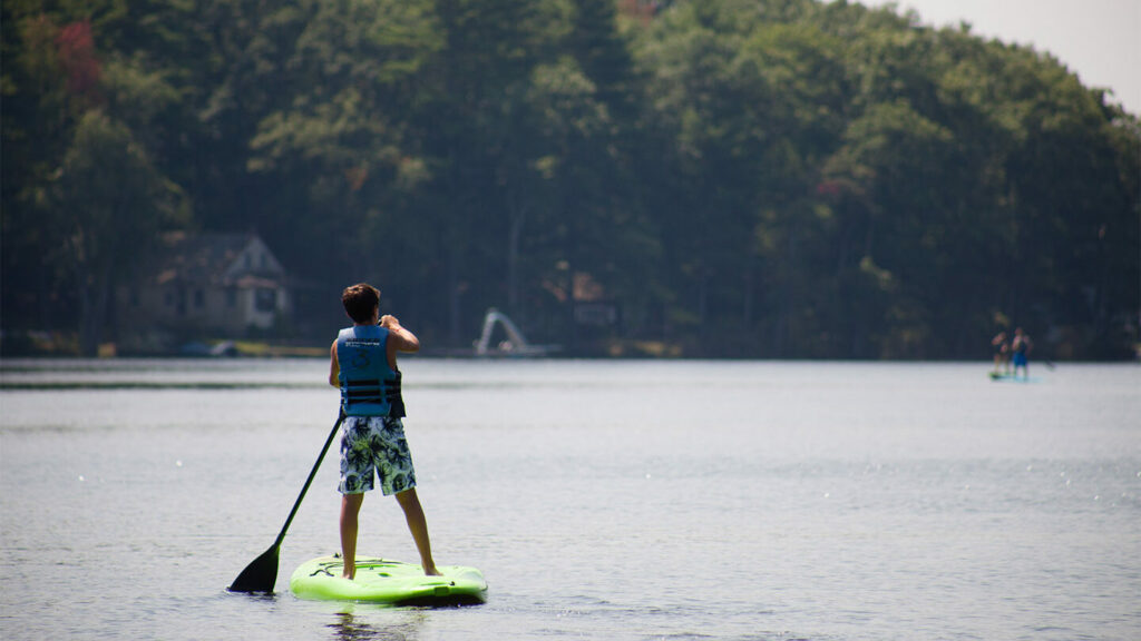 Young man on stand up paddleboard on Lake Teedyuskung.