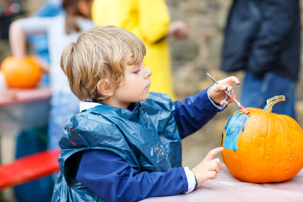 A kid painting a pumpkin at one of the local Pocono fall festivals.