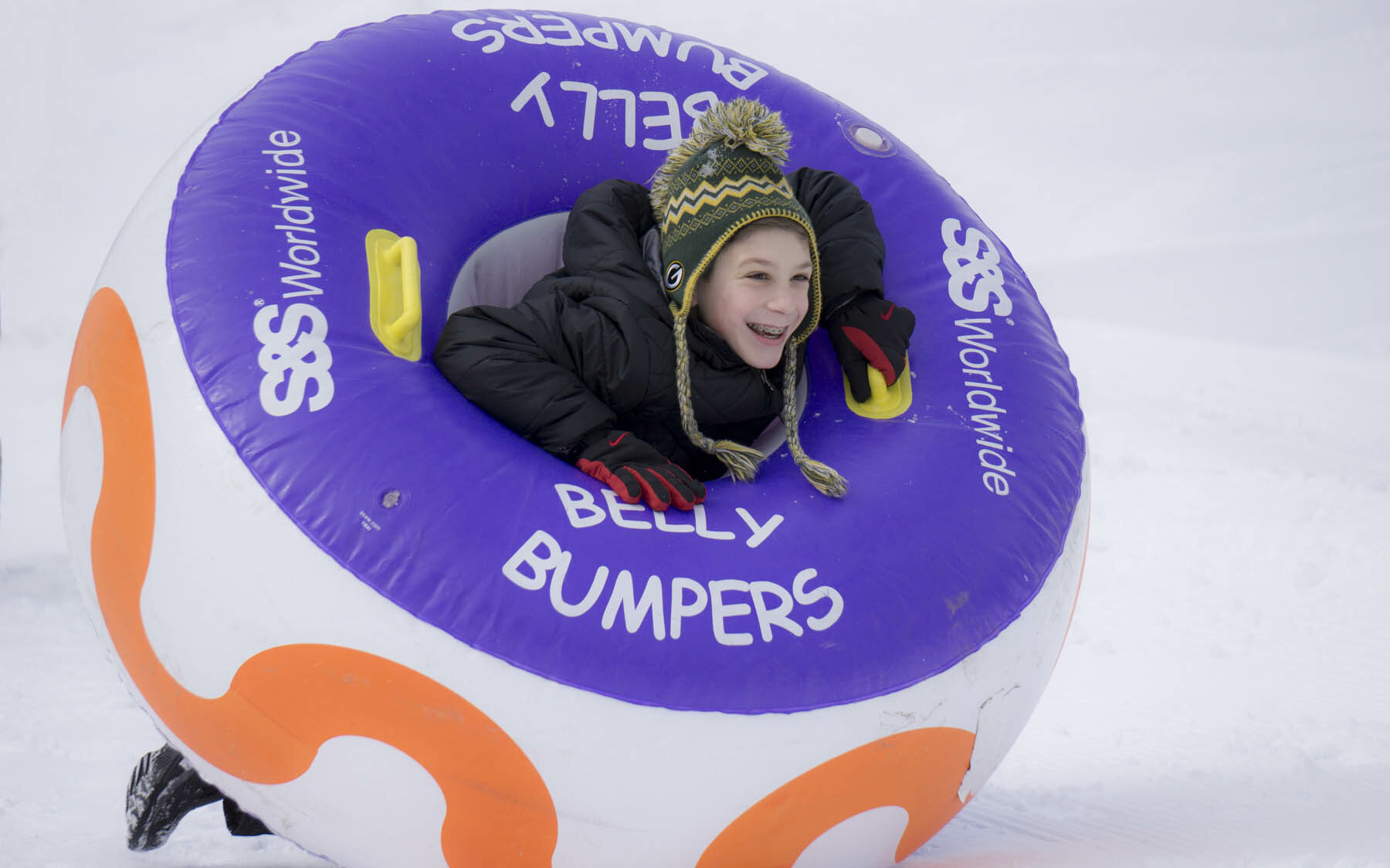Young person in a belly bumper inner tube in winter.