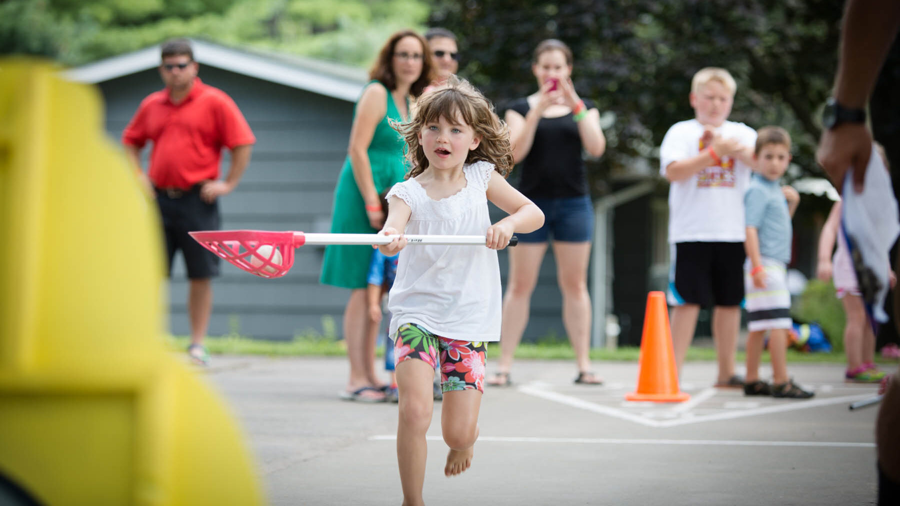 Young girl running with kids lacrosse raquet and ball.