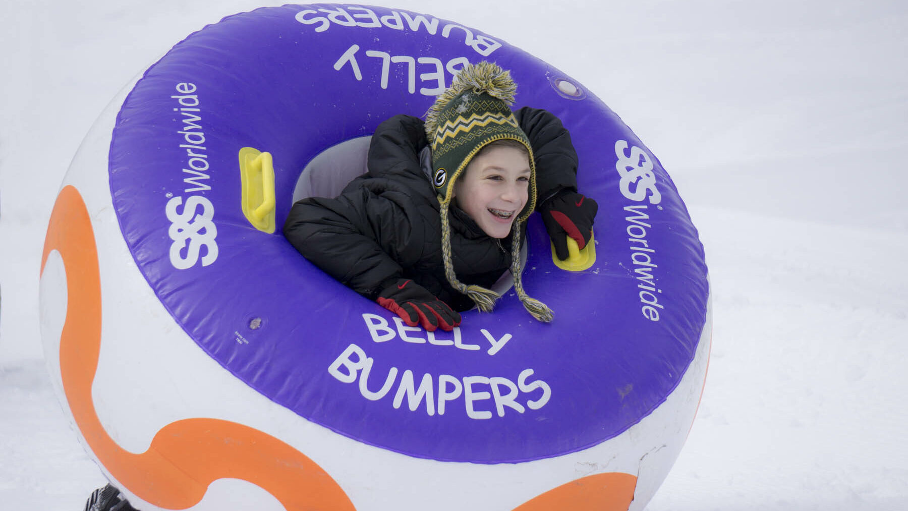 Young person in a belly bumper inner tube in winter.