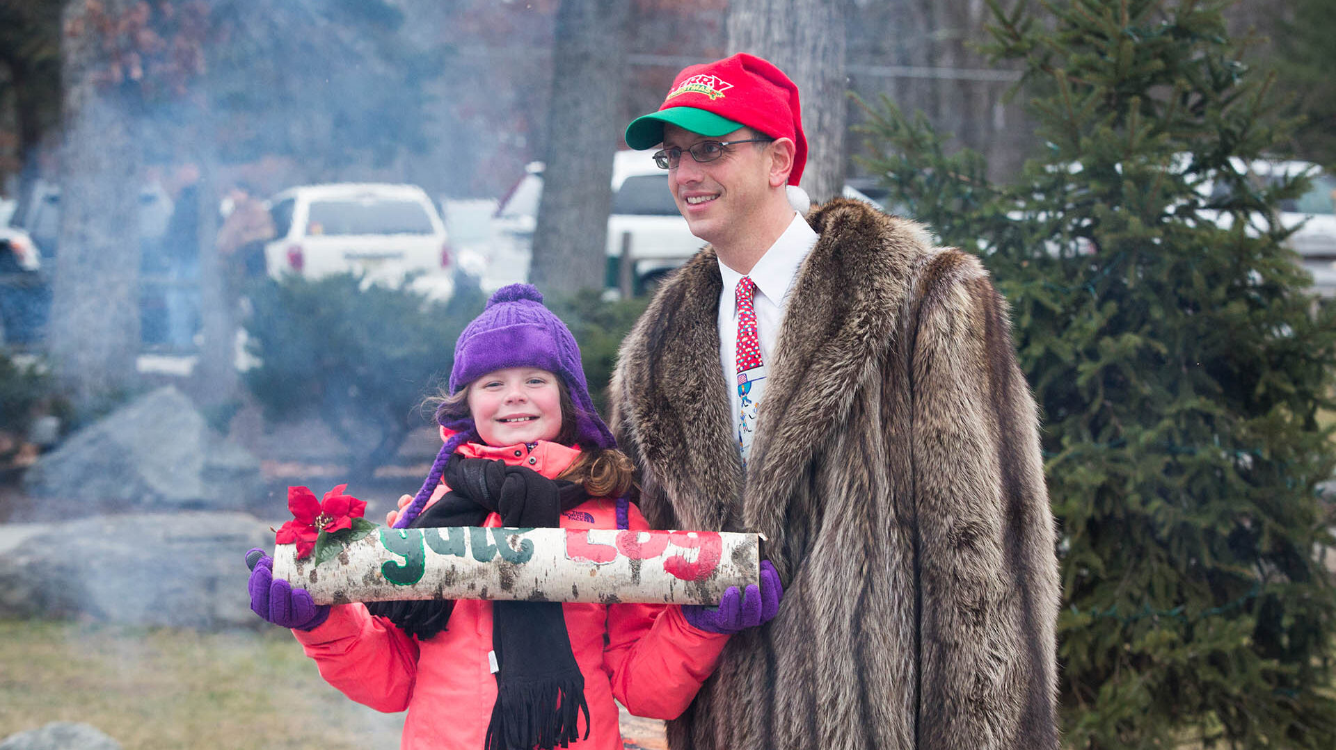 Child holding yule log next to Woodloch event coordinator.
