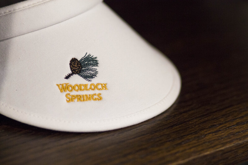 White visor. Text: Woodloch Springs