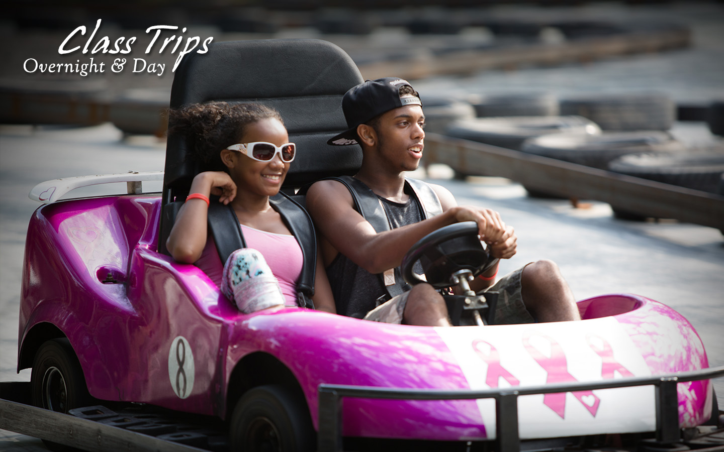 Young man and young woman in a gokart. Text: Class Trips, overnight and day.