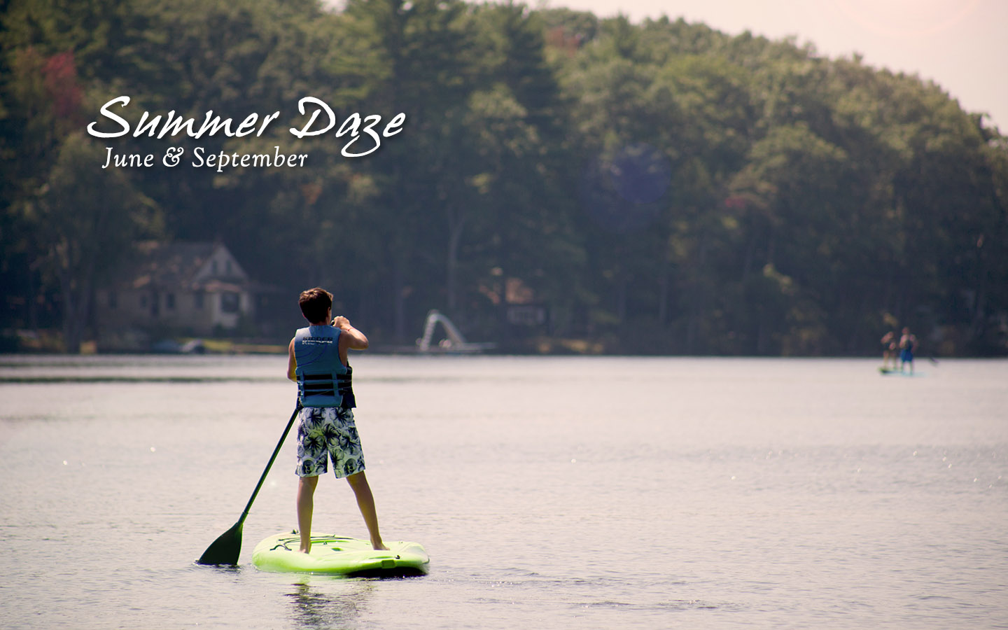 Young person on Lake Teedyuskung on a stand up paddleboard. Text: Summer Daze, June and September.