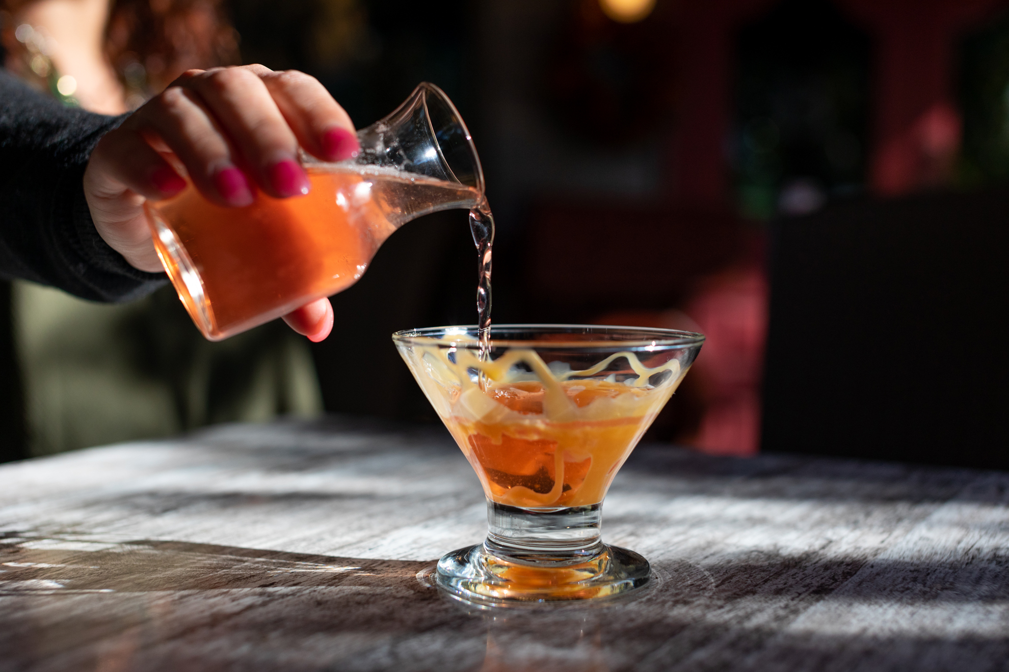 Bartender pouring cocktail.