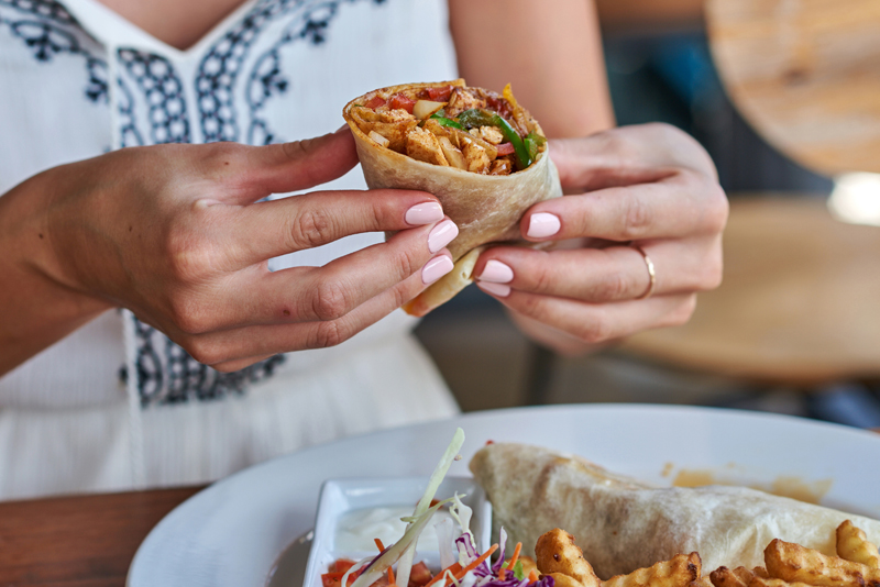 Close up of person holding chicken wrap.