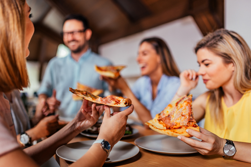 Women holding pizza slices.