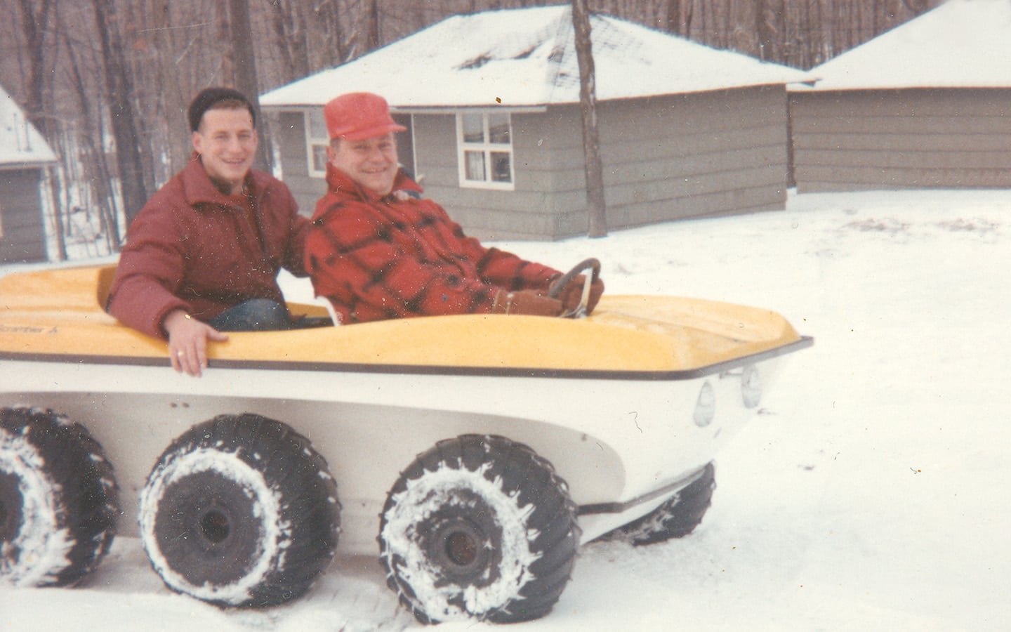Historic photo of two men in six wheel snowmobile.