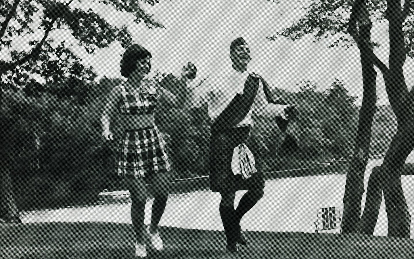 Historic photo of woman dancing with a man in Scottish clothes.